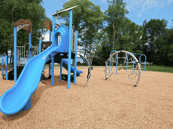Playground at Hibou Conservation Area with trees and lake in background.